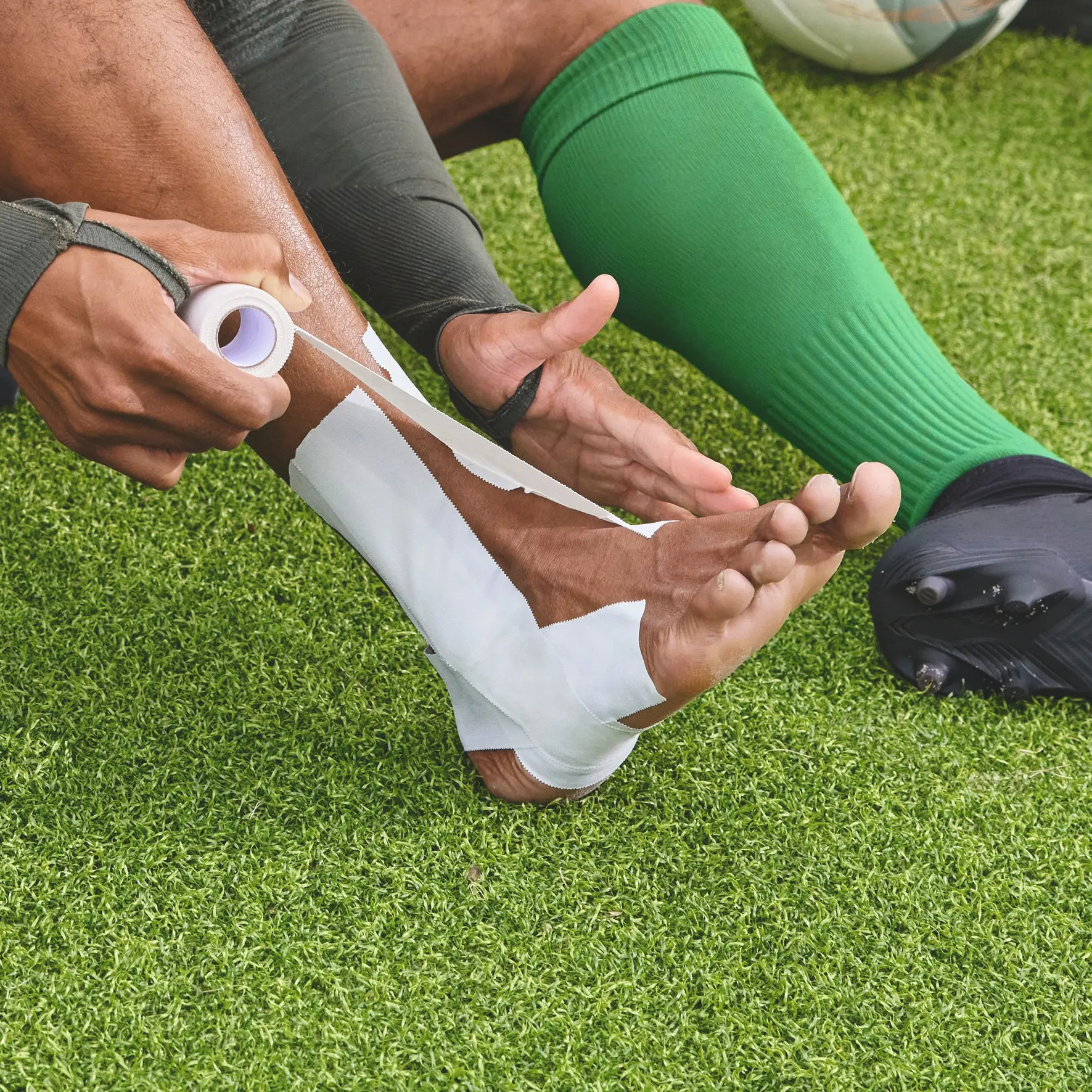 Application d’une bande Strappal® sur le pied d’un joueur de football, illustrant ses usages recommandés en contention articulaire rigide, traumatologie sportive, orthopédie et tractions adhésives continues.